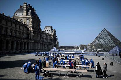 El pasado martes, un ejército de voluntarios comenzó a pegar una colosal imagen de papel de 14.800 metros cuadrados sobre el patio para preparar la ilusión de la pirámide. En la imagen, voluntarios trabajando en la preparación de la instalación en el patio principal Cour Napoleon del Museo del Louvre en París.