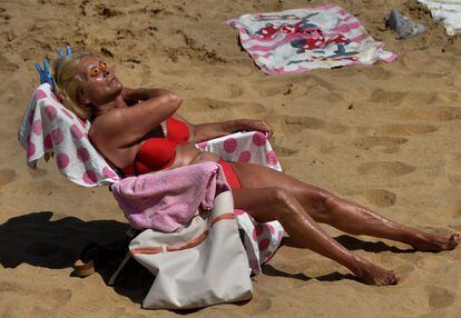 Una mujer toma el sol en la playa de San Lorenzo de Gijón.