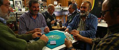 Cuatro hombres juegan a las cartas en el bar La Muralla, en Villaverde (Madrid).