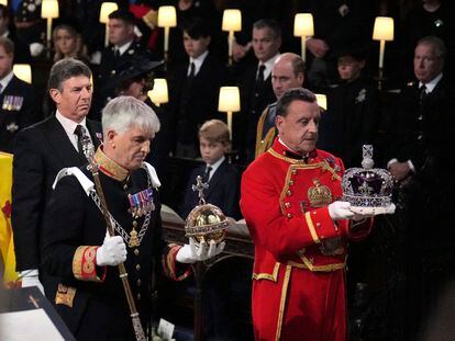 The Imperial State Crown, orb and sceptre are carried to the Dean of Windsor to be placed on the high altar  during the committal service for Queen Elizabeth II, at St. George's Chapel, in Windsor, England, Monday Sept. 19, 2022. The Queen, who died aged 96 on Sept. 8, will be buried at Windsor alongside her late husband, Prince Philip, who died last year.  (Victoria Jones /Pool Photo via AP)