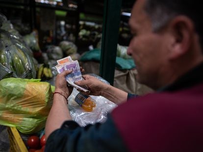 Un vendedor cuenta su dinero en la plaza de Paloquemao, en Bogotá.