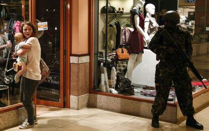 Un soldado apostado en el centro comercial ante una mujer y su hijo.