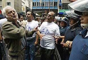 Varios manifestantes entonan cánticos frente a la línea de policías en la manifestación anti-Chávez de Caracas.