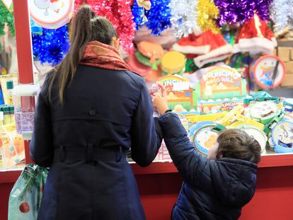 Una mujer y un niño contemplan un puesto del mercado navideño instalado en la Plaza Mayor de Madrid.