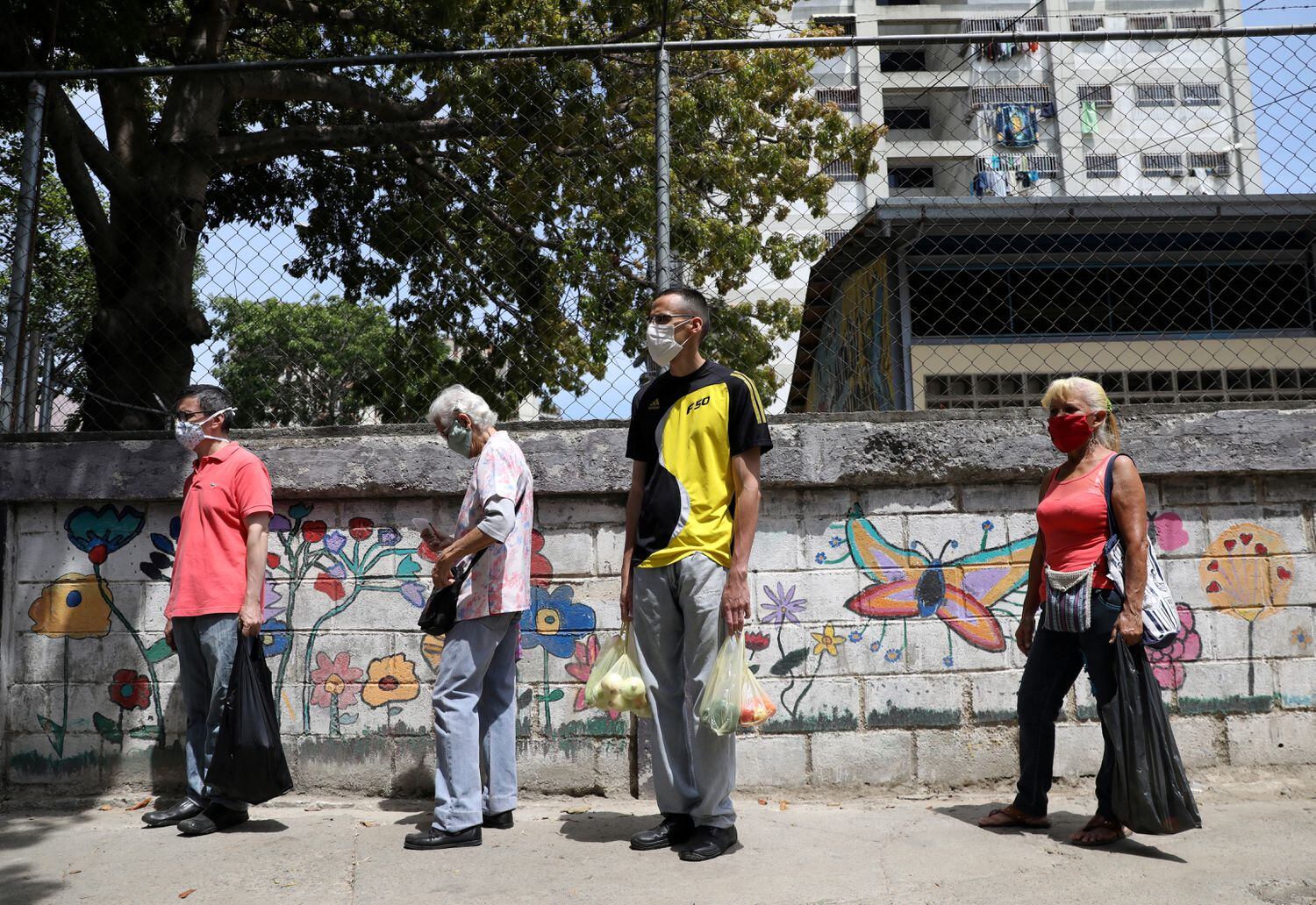 Habitantes de Caracas hace fila para acceder a un mercado de verduras, este jueves.