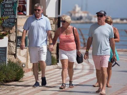 Varios turistas pasean por el paseo marítimo de la playa de Santa Ana de Arroyo de la Miel, Benalmádena (Málaga).