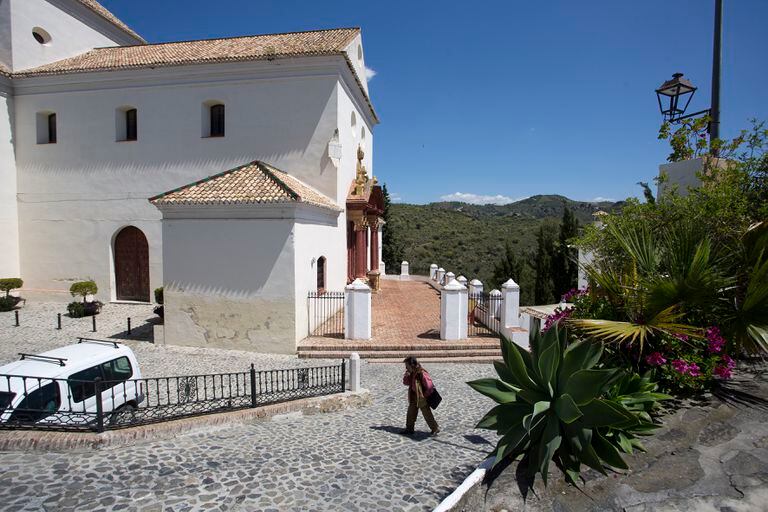 Un vecino pasea junto a la iglesia de Macharaviaya, en Málaga, pueblo sin casos positivos de coronavirus.