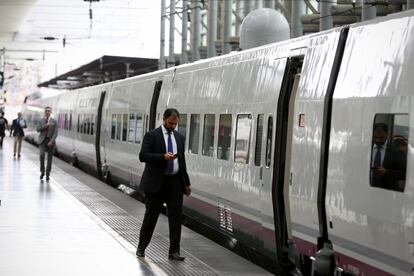 Un pasajero mira el móvil antes de entrar en un tren AVE