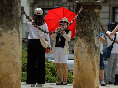 Unos turistas se fotografían el pasado martes junto al Archivo de Indias de Sevilla bajo la intensa ola de calor que mantiene en alerta a casi toda España.