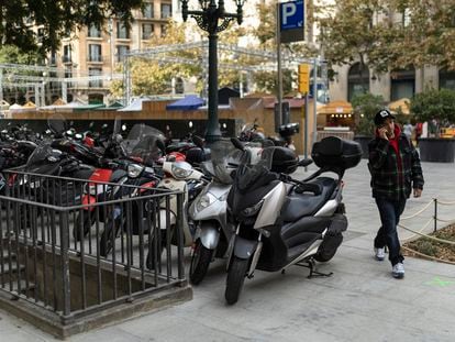 Un hombre camina entre motos y un alcorque, en la plaza de la Catedral de Barcelona, este viernes.