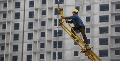 Un obrero trabaja sobre un andamio para encofrado en las obras de construcci&oacute;n de un edificio