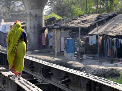 Una mujer cruza un improvisado puente en una barriada de chabolas de Calcuta.