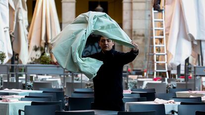 Un trabajador de la hostelería prepara una mesa en una terraza.