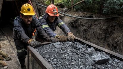 Dos mineros empujan un vagón de carbón fuera de una mina en Cucunuba, Colombia.