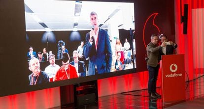 Videollamada 5G entre Albert Buxadé, de Vodafone, en la pantalla, y el secretario de Estado para la Sociedad de la Información, José María Lasalle (en el atril)