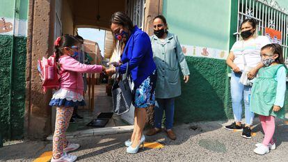 Una maestra toma la temperatura a una alumna en un colegio en León, Guanajuato.