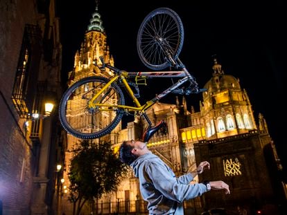 Christian López, con 95 récords Guiness, sostiene una bicicleta con su barbilla en la plaza del Ayuntamiento de Toledo.