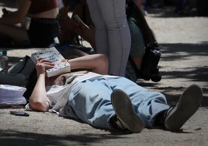 Un lector tendido en el Paseo de Coches en la Feria del Libro de Madrid este sábado.