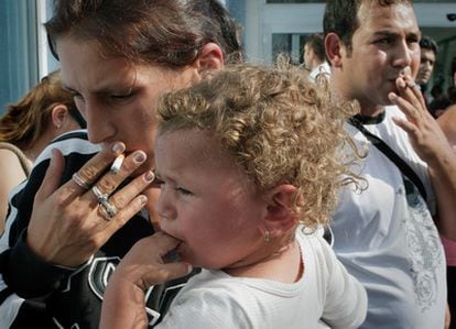 Mariana Sasz, con su hija en brazos, y su marido Ionut Sasz, fuman a su llegada a Bucarest tras ser deportados desde Francia.