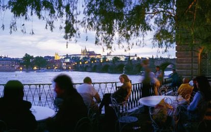 Una terraza junto al río Moldava, en Praga, con el puente de Carlos al fondo.