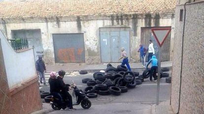 Un grupo de personas  levanta una barricada en la entrada del barrio melillense de la Ca&ntilde;ada. 