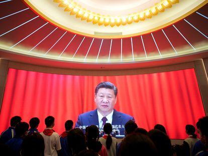 Un grupo de jóvenes frente a una pantalla en la que Xi Jinping pronuncia un discurso.