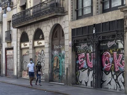Una parella passejant pel carrer Ferran de Barcelona, amb la majoria d'establiments tancats.