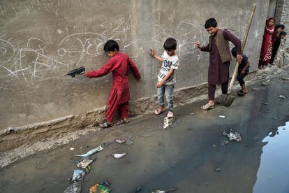 Niños tratan de pasar por una calle en la que se ha vaciado una fosa séptica en un barrio próximo a la zona de Sarai Shamali de Kabul.