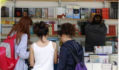 Un grupo de jóvenes examina libros en una caseta de la feria de Valencia.