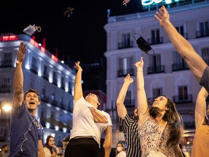 Varias personas celebran el fin del uso obligatorio de la mascarilla en espacios abiertos en la Puerta del Sol, en Madrid.