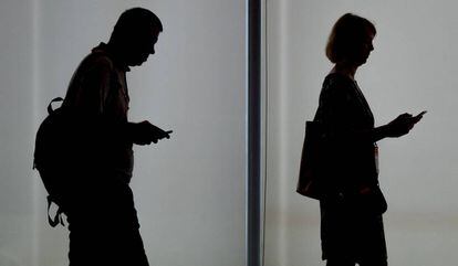 Dos personas usando sus teléfonos móviles.