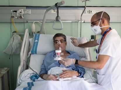 Jordi Soriano, primer paciente poscovid con trasplante de pulmón en España, realiza ejercicios respiratorios con su fisioterapeuta, Bernat Planas.