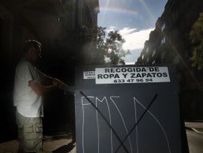 Un hombre deposita una bolsa en un contenedor de ropa.