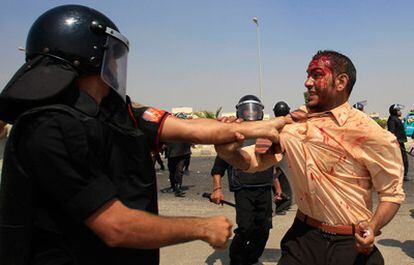 Un policía agarra a un manifestante anti-Mubarak, que previamente había sido golpeado por manifestantes a favor del expresidente.