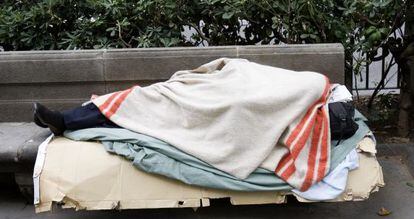 Un sin techo durmiendo en un banco de Barcelona.