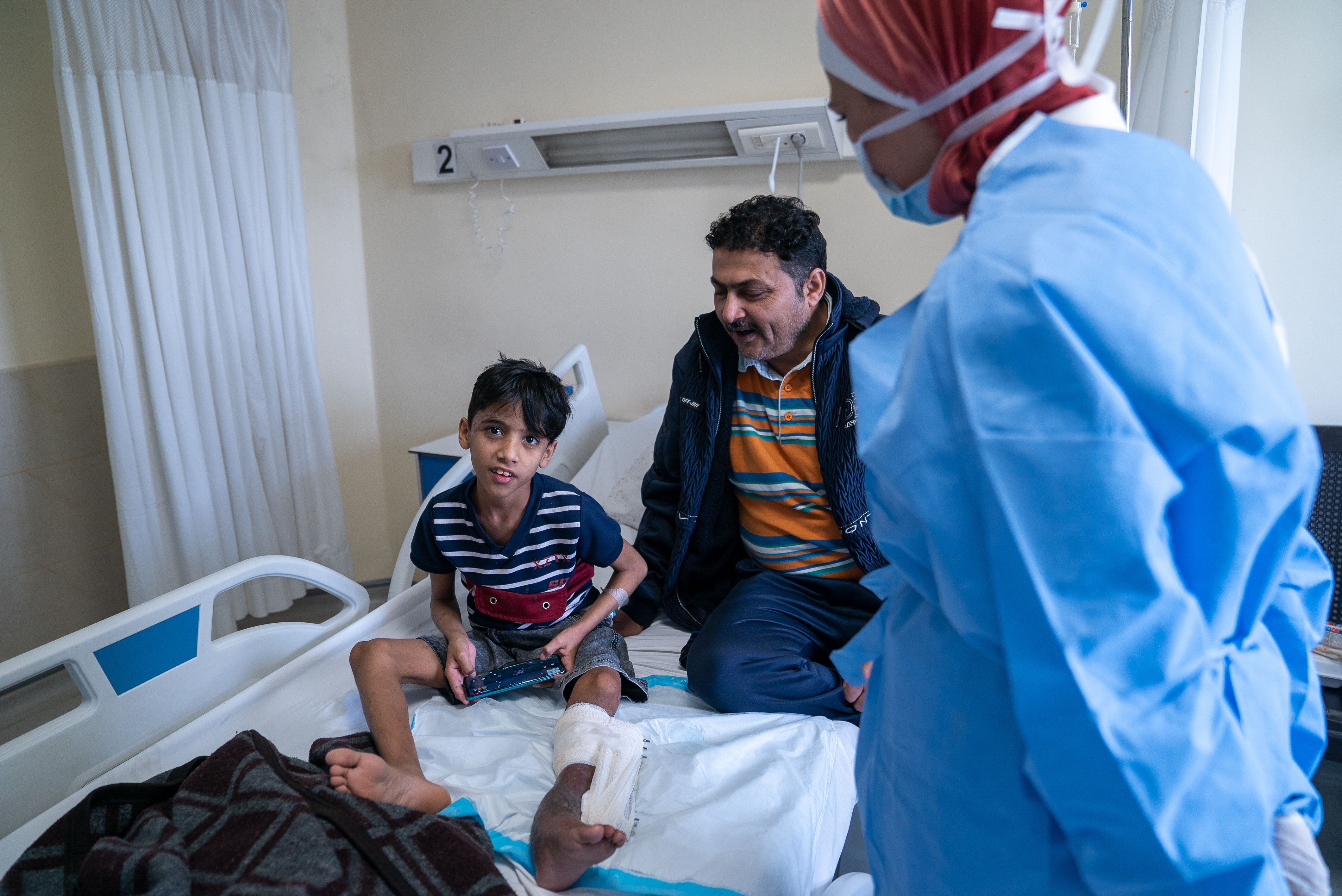 Riad Mohamed Alí, yemení de 10 años, y su padre son atendidos en una habitación del hospital por la doctora iraquí Nagham Hussein.