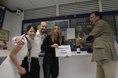 Ana Albert, con el cartel, dueña de la administración de loteria nº 41 de Las Rozas, donde ha caído el tercer premio de la Loteria Nacional de Navidad.