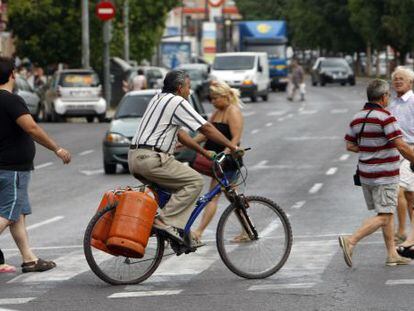 Un hombre carga dos bombonas de butano en una bicicleta