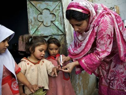 Una trabajadora sanitaria marca el dedo de una ni&ntilde;a para indicar que ha sido vacunada contra la polio, en Karachi (Pakist&aacute;n).