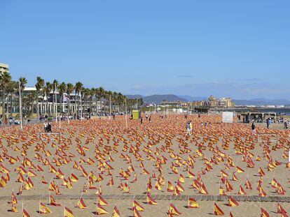 Varias personas visitan la playa de la Patacona de Alboraya en la que se han colocado un total de 53.000 banderas de España.