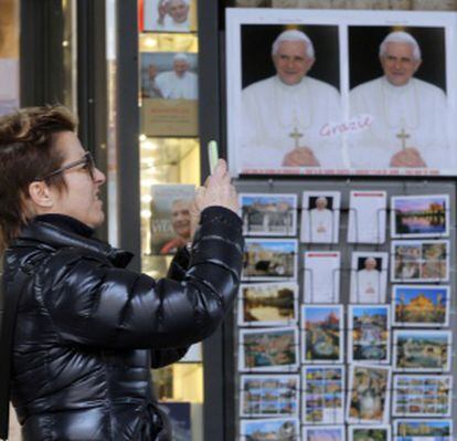 Una mujer fotografía una imagen de Benedicto XVI