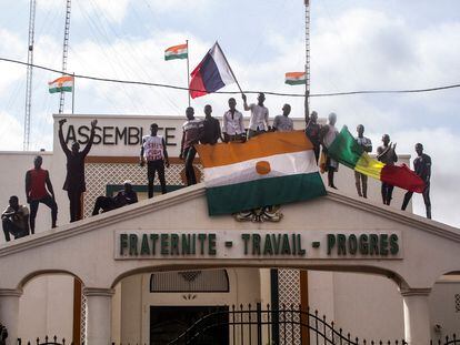 Manifestantes favorables al golpe de Estado encaramados a la Asamblea Nacional con banderas de Níger, Rusia y Malí, el 3 de agosto en Niamey.