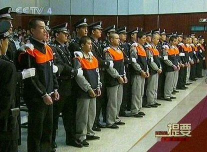 Imagen captada de la televisión china que muestra a un grupo de acusados de las revueltas étnicas de julio pasado custodiados por sus guardianes.