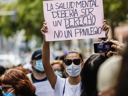 Una mujer muestra una pancarta durante una manifestación por la salud mental.