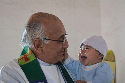 El padre jesuita Javier Campos Morales “El Gallo”, con un bebé en brazos.