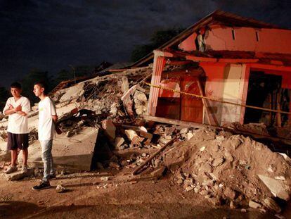 Unos j&oacute;venes permanecen junto a unos escombros durante el velorio de un allegado en Manta (Ecuador).