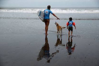 La instructora Nette Klement encamina al niño Lucas Rivera al mar para darle una lección de surf.