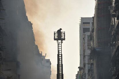 Un bombero mira hacia el fuego declarado en un edificio residencial en de Hong Kong. En el incendio murieron ocho personas y otras 24 resultaron heridas.