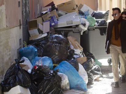 Dos vecinos de M&aacute;laga sortean la basura acumulada ayer en un contenedor por la huelga de los servicios de limpieza