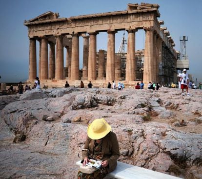 Una mujer consulta un libro en la Acr&oacute;polis de Atenas. 